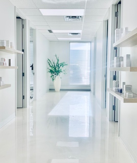 Derma Vital clinic hallway with natural light, product displays, and fresh greenery