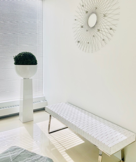 Modern waiting area at Derma Vital with designer bench and artistic sunburst mirror